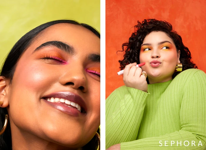 Close-up portrait of two diverse models with vibrant makeup against bright orange and yellow backgrounds, retouched by Iren Skaarnes.