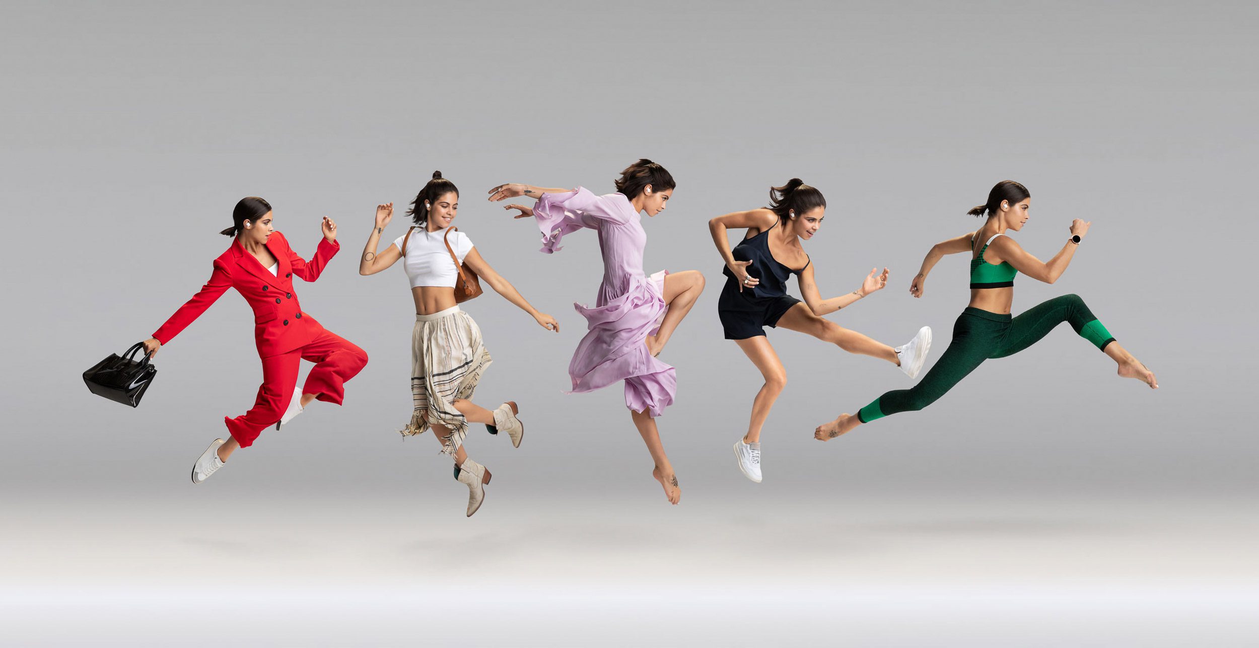 Five women are mid-air in different outfits: a red suit, a crop top with a skirt, a dress, a tank top with shorts, and activewear.