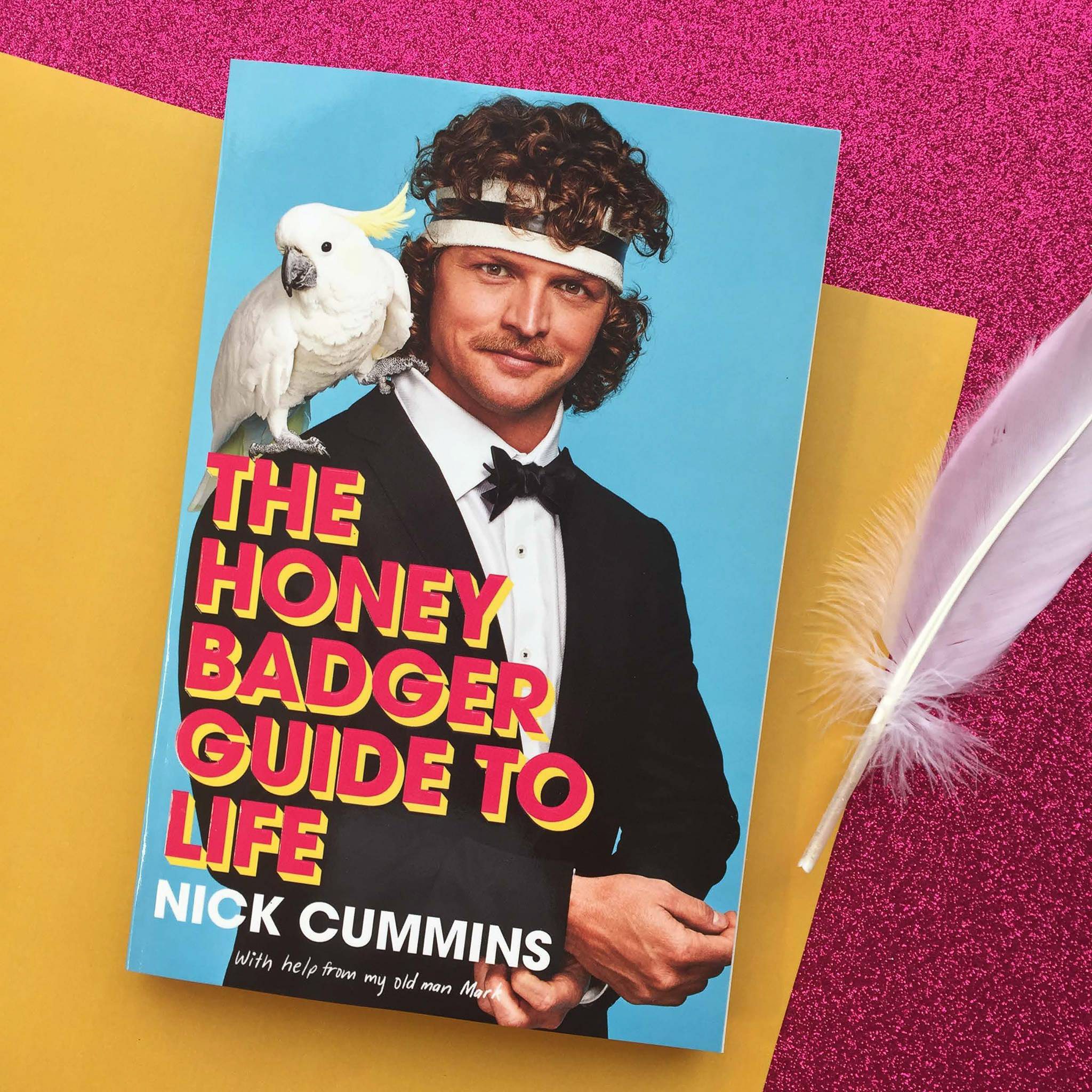 Book cover featuring a man in a tuxedo with a cockatoo on his shoulder, set against a pink glitter background and gold paper.