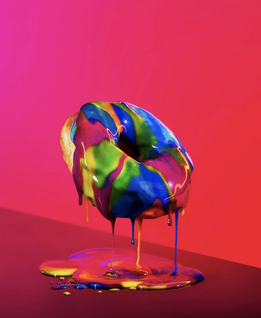 Eye-level shot of a donut covered in multicolored glaze on a dark surface against a vibrant, gradient red and magenta backdrop.