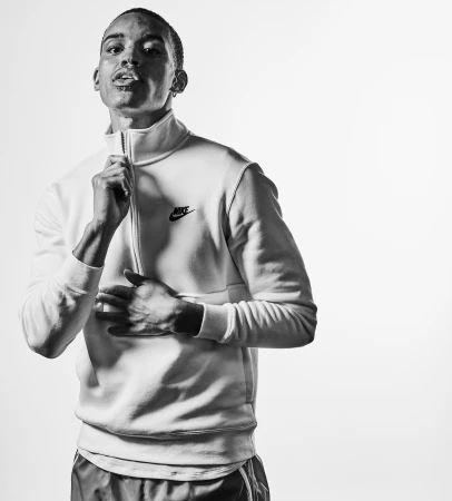 Monochrome portrait of a young man wearing a Nike quarter-zip sweatshirt against a seamless white background.
