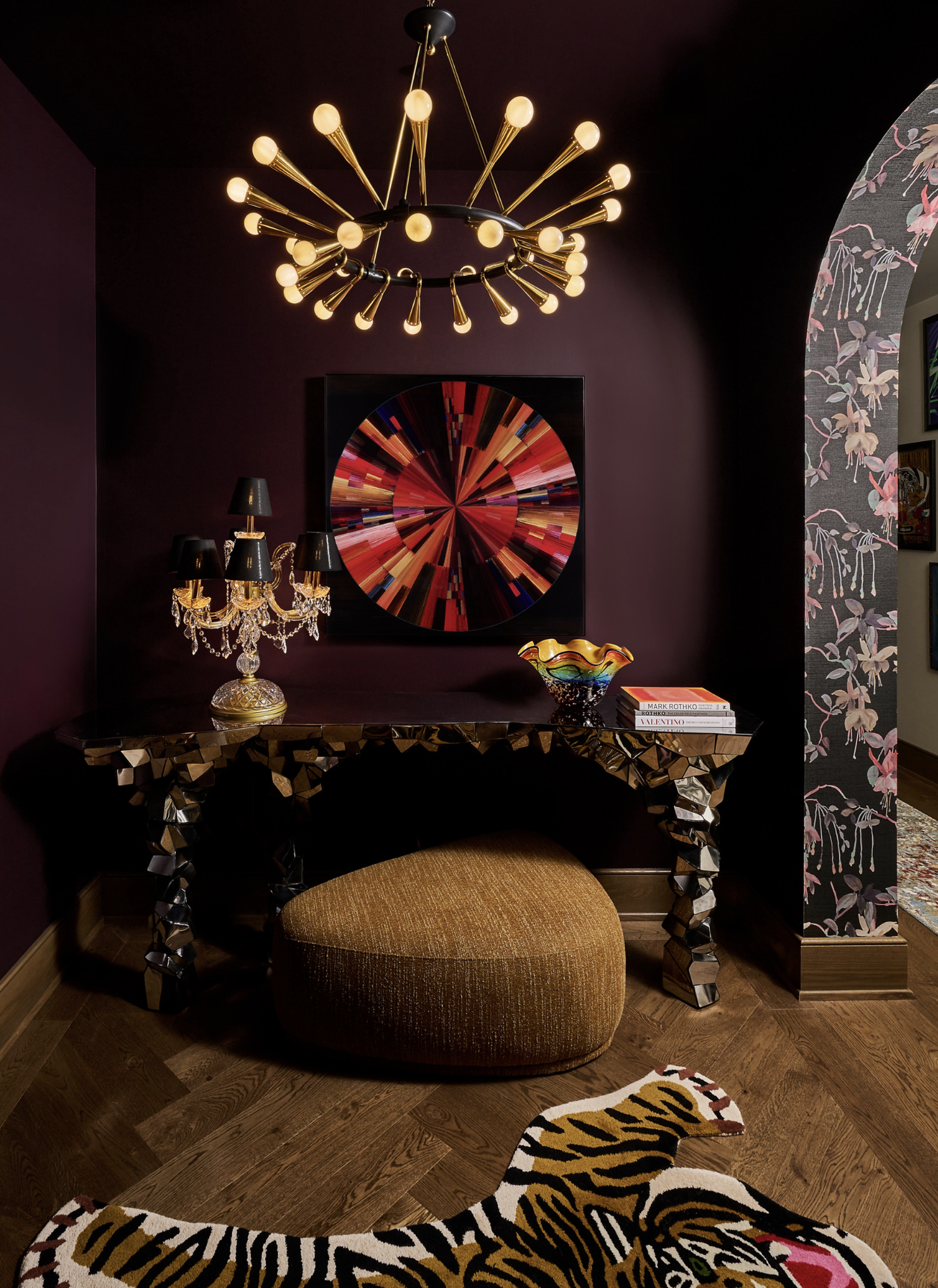 Interior design featuring a console table adorned with decorative items, illuminated by a modern chandelier, and complemented by a tiger-striped rug.