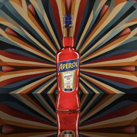 Aperol bottle on a reflective surface against a radiating patterned background, creating a vibrant and eye-catching still life.