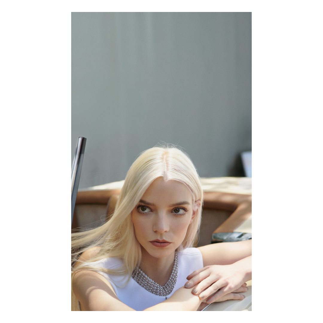 Portrait of blonde woman with pearl necklace wearing white top leaning on boat with producer Camille Peck.
