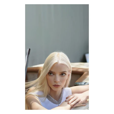 Portrait of blonde woman with pearl necklace wearing white top leaning on boat with producer Camille Peck.