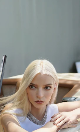 Close-up portrait of a blonde woman wearing a white top and a heavy silver pearl necklace