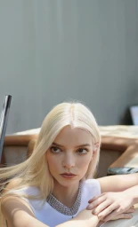 Close-up portrait of a blonde woman wearing a white top and a heavy silver pearl necklace