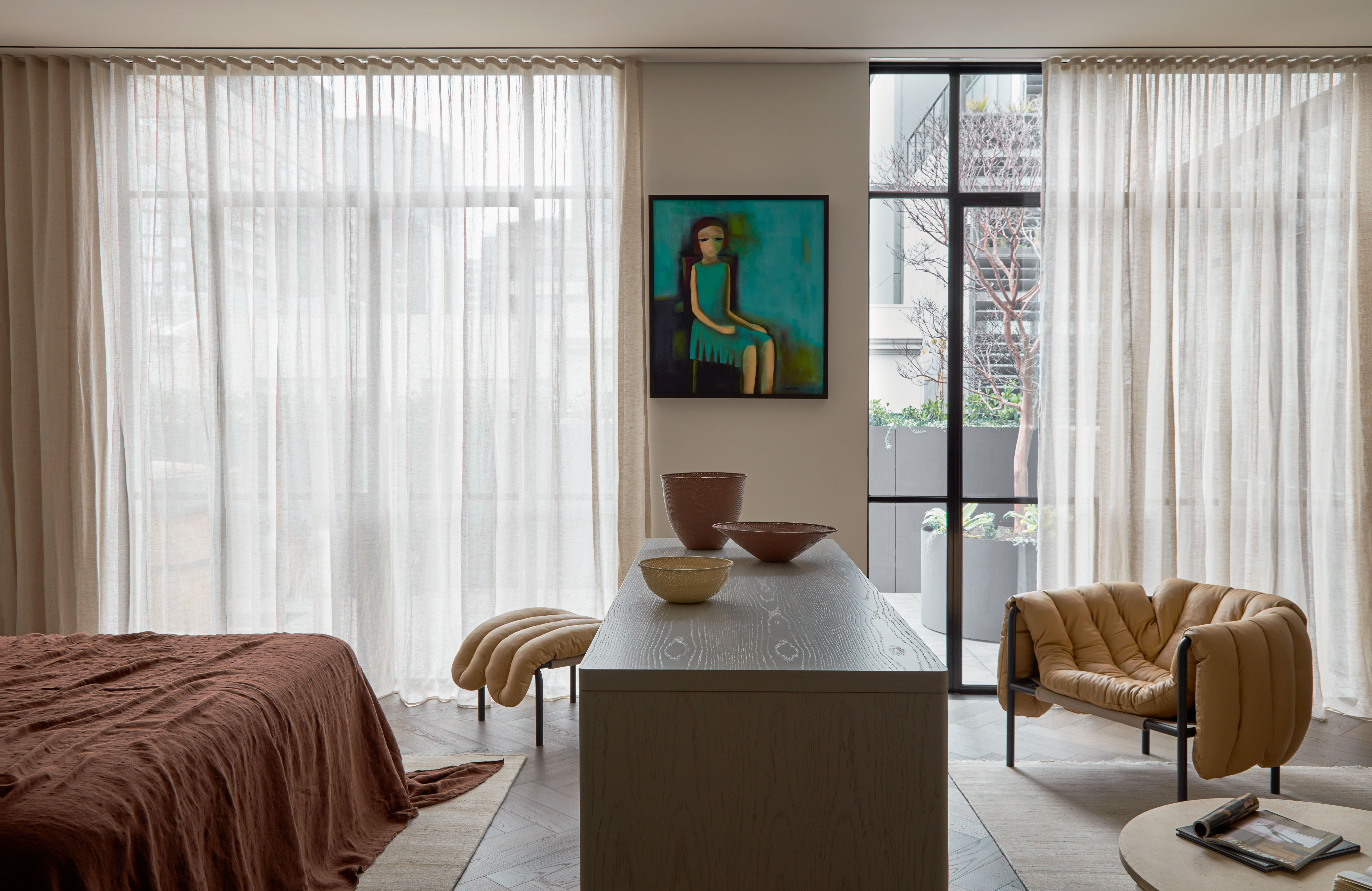 Contemporary living room showcasing an artwork, stylish furniture, and natural light filtering through sheer curtains, creating a serene ambiance.