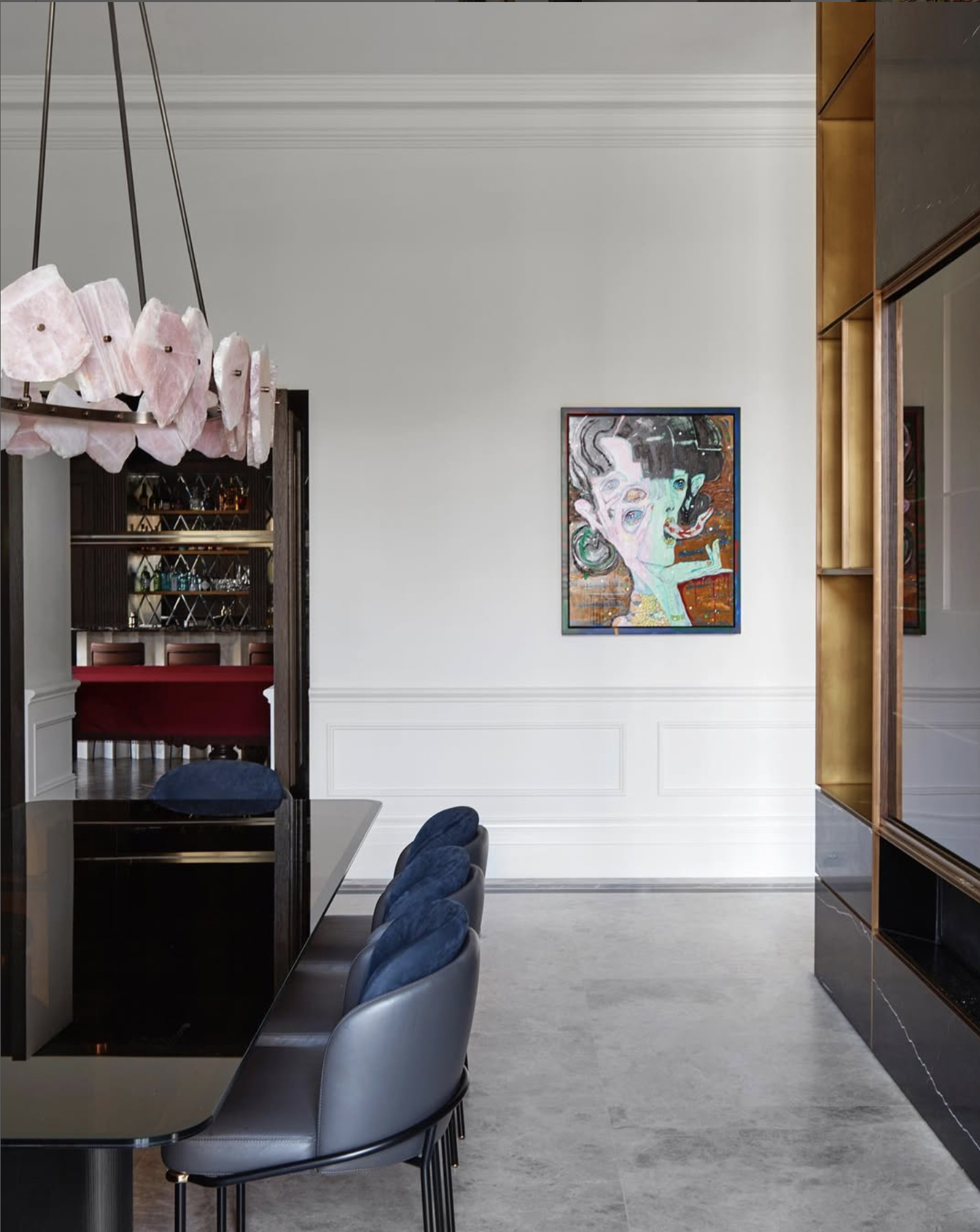 Modern dining room features a black table, gray chairs, and a unique chandelier. Artwork hangs on the white walls, adding to the decor.