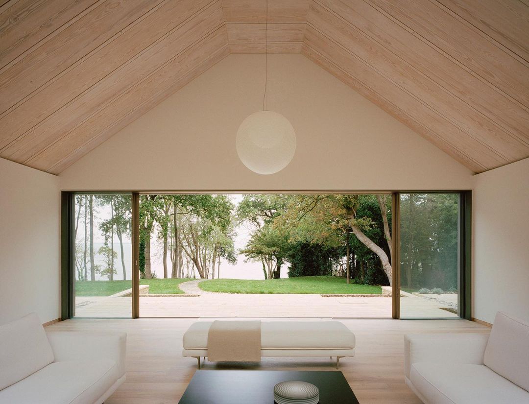 Modern interior featuring white furniture and a large window with a view of a green lawn and trees, creating a bright and open space.