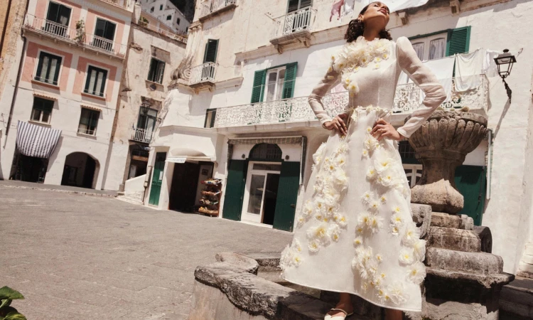 Model in a white floral applique dress posing in a European public square with traditional buildings