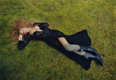 Angelina Kendall lying on moss-covered ground wearing a black lace dress and riding boots for Harper's Bazaar Australia.