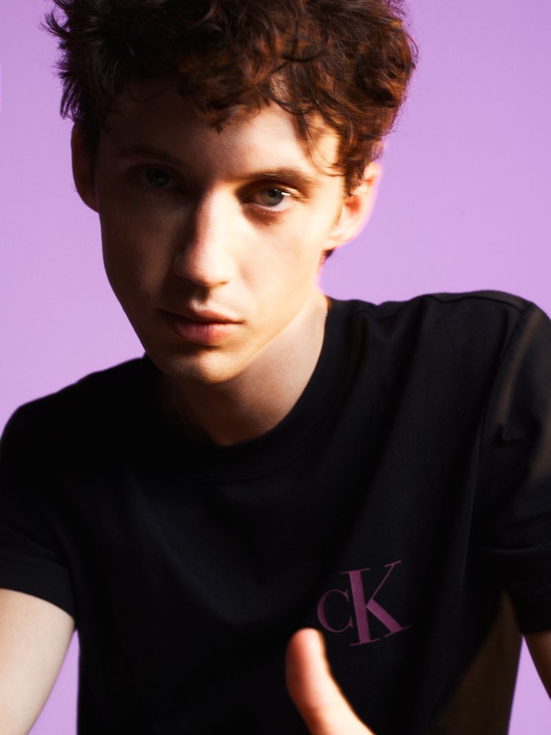Portrait of Troye Sivan wearing a black t-shirt against a solid purple backdrop for Russh magazine