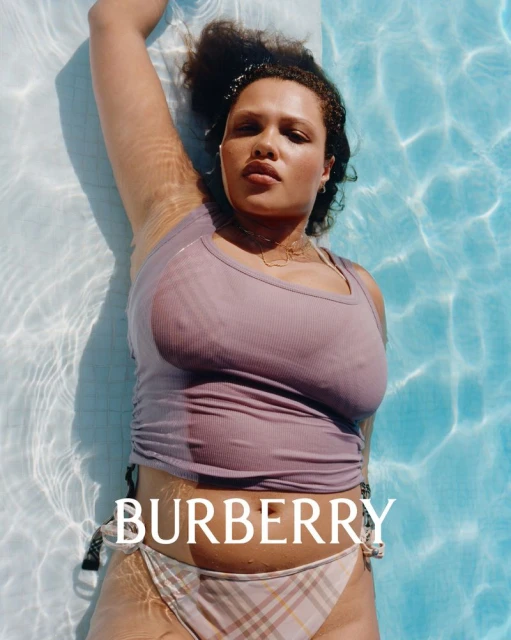 Woman lays in a pool wearing a lilac top and Burberry plaid bikini, bathed in bright sunlight, the Burberry logo shown on the water.