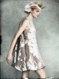 Model in a floral print sleeveless dress with a floral headpiece against a mottled grey background