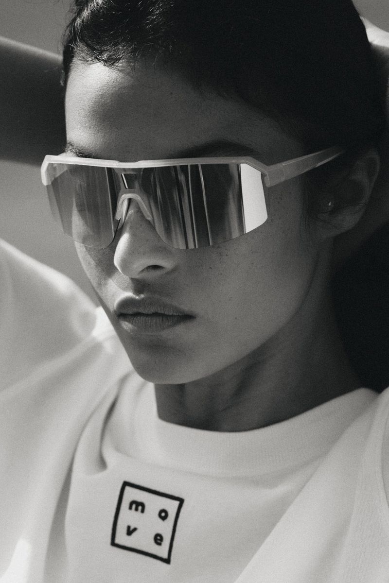 Woman wearing oversized sunglasses and a white t-shirt with 'move' printed on it, close-up black and white fashion shot.