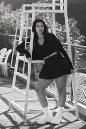 Devyn Garcia leaning against a white umpire chair wearing an athletic top and pleated skirt for H&M Move