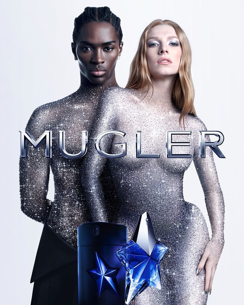 Perfume ad featuring a Black man and a light-skinned woman in glittering bodysuits, with the 'Mugler' logo and perfume bottles visible.