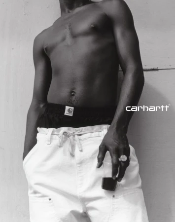 Monochrome torso portrait of a shirtless man wearing white trousers and black briefs for Carhartt WIP SS25