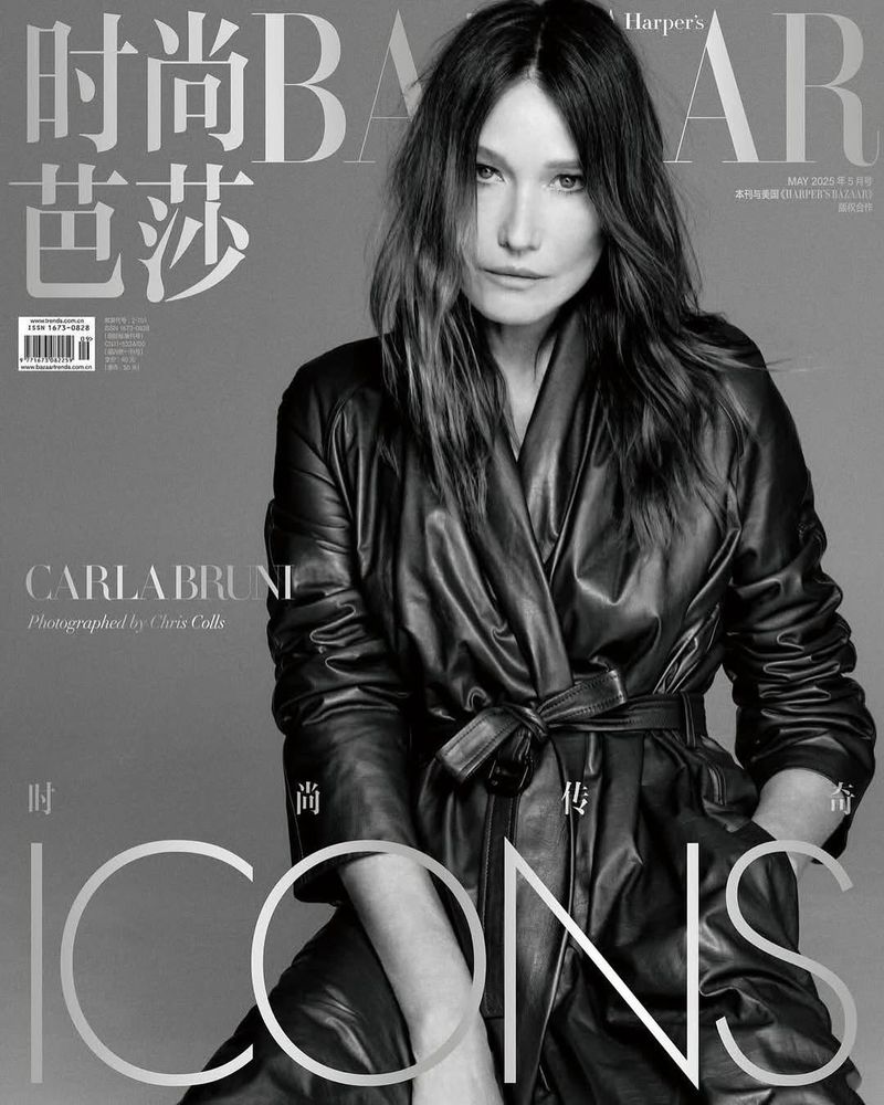 Black-and-white Harper's Bazaar magazine cover featuring Carla Bruni, wearing a leather trench coat and posing against a gray backdrop.