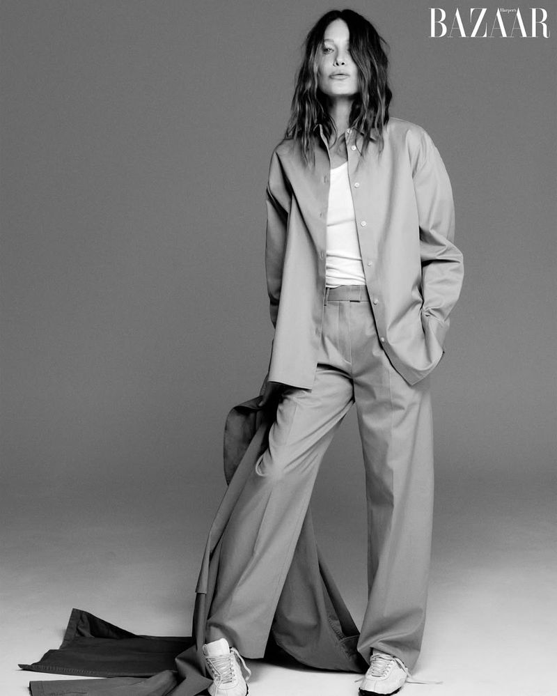 Carla Bruni in an unbuttoned shirt and wide-leg trousers posing in a studio for Harper's Bazaar China.