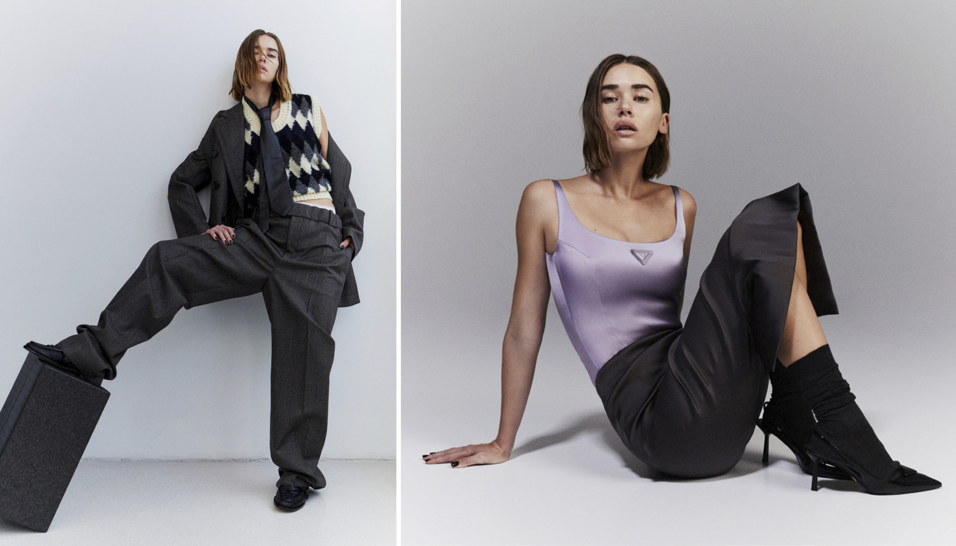 Two women pose in studio wearing fashionable outfits. One stands with foot on block, the other sits. Grey, lavender, and black color scheme.