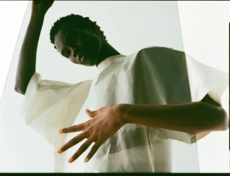 Model in a white t-shirt captured from a low angle looking through a transparent panel for Dapper Dan Magazine