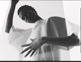 Monochrome low angle portrait of a model wearing a white t-shirt against a light background for Dapper Dan Magazine