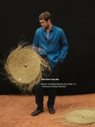 Will Chalker wearing a blue linen shirt holding a woven straw mat for Massimo Dutti Ibiza Roots