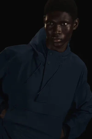 Portrait of an adult Black male model wearing a blue pullover shirt in a studio with dark background. Fashion and beauty photography.