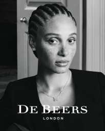 Black-and-white portrait of Adwoa Aboah wearing diamond jewelry and a black top against an interior doorway.
