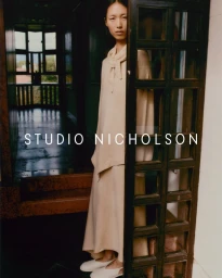 Model in cream knit top and skirt posing in a doorway for Studio Nicholson