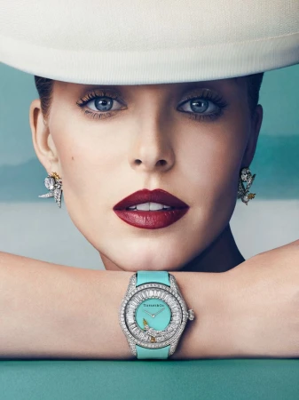 Close-up portrait of Abby Champion wearing a wide-brimmed white hat, diamond earrings, and a turquoise watch resting on her arms