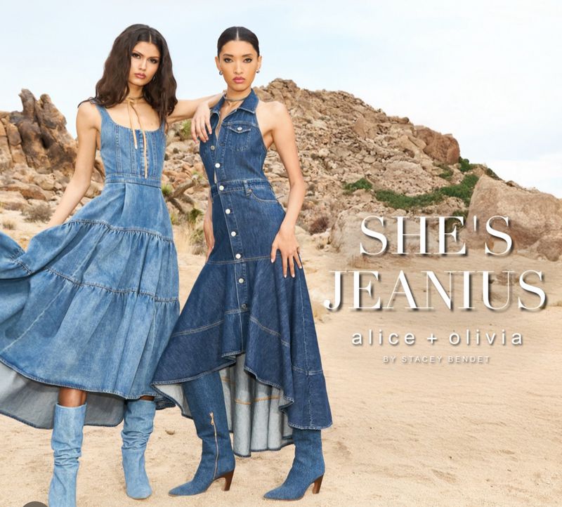 Two women model denim dresses and knee-high heeled boots in a desert landscape featuring rock formations, styled for a fashion editorial.
