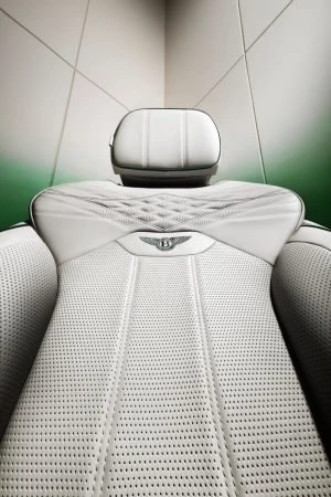 Close-up studio shot of a white Bentley car seat featuring perforated leather, diamond stitching, and the Bentley logo centered on the upper seat.
