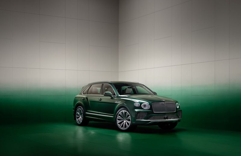 Green Bentley Bentayga SUV in a studio setting with green and gray gradient backdrop. Luxury automotive photography.