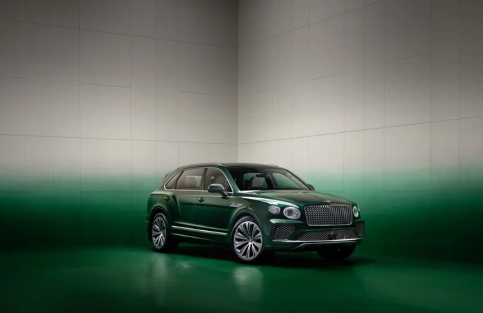 Green Bentley Bentayga SUV in a studio setting with green and gray gradient backdrop. Luxury automotive photography.