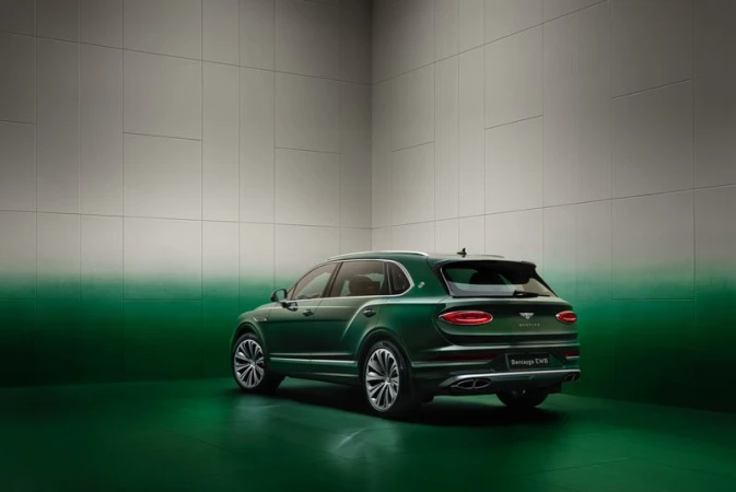 Rear view of a dark green Bentley Bentayga SUV in a photo studio, featuring detailed rims and a modern automotive design.