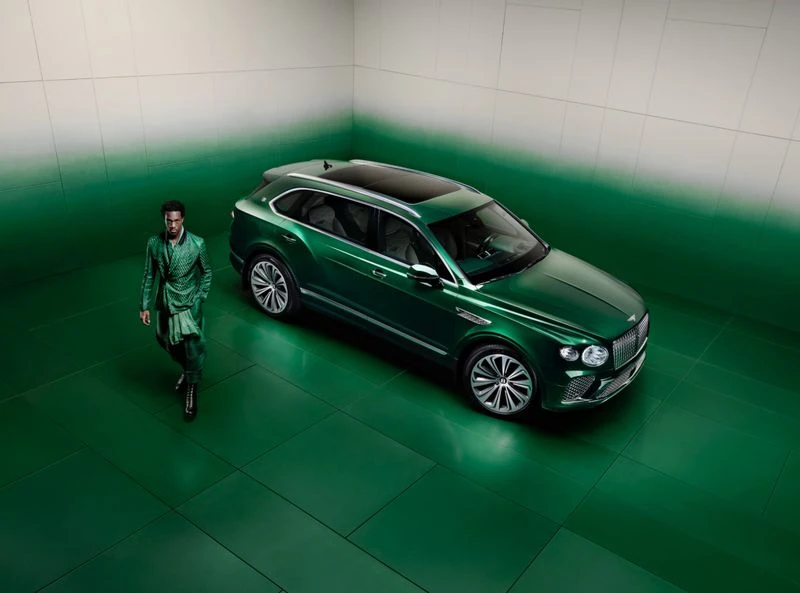 Green Bentley SUV in a studio setting with a stylish man in a matching green suit, presenting a unified and sophisticated automotive image.