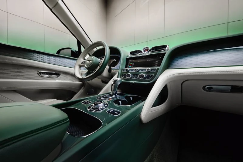 Interior of green and cream Bentley Bentayga SUV featuring steering wheel, dashboard, and center console with chrome accents.