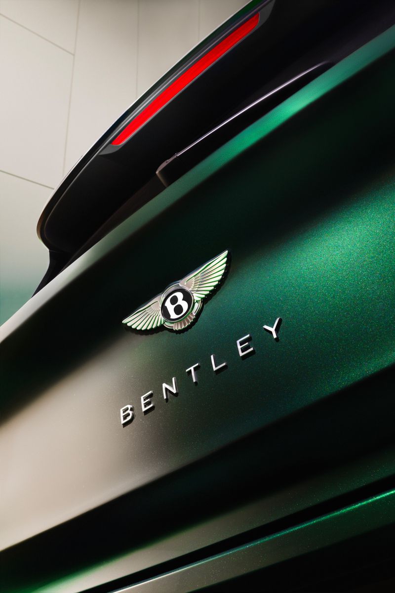 Close-up of a green Bentley automobile showcasing the logo and brand name on the exterior of the vehicle, creating a sleek, luxurious look.