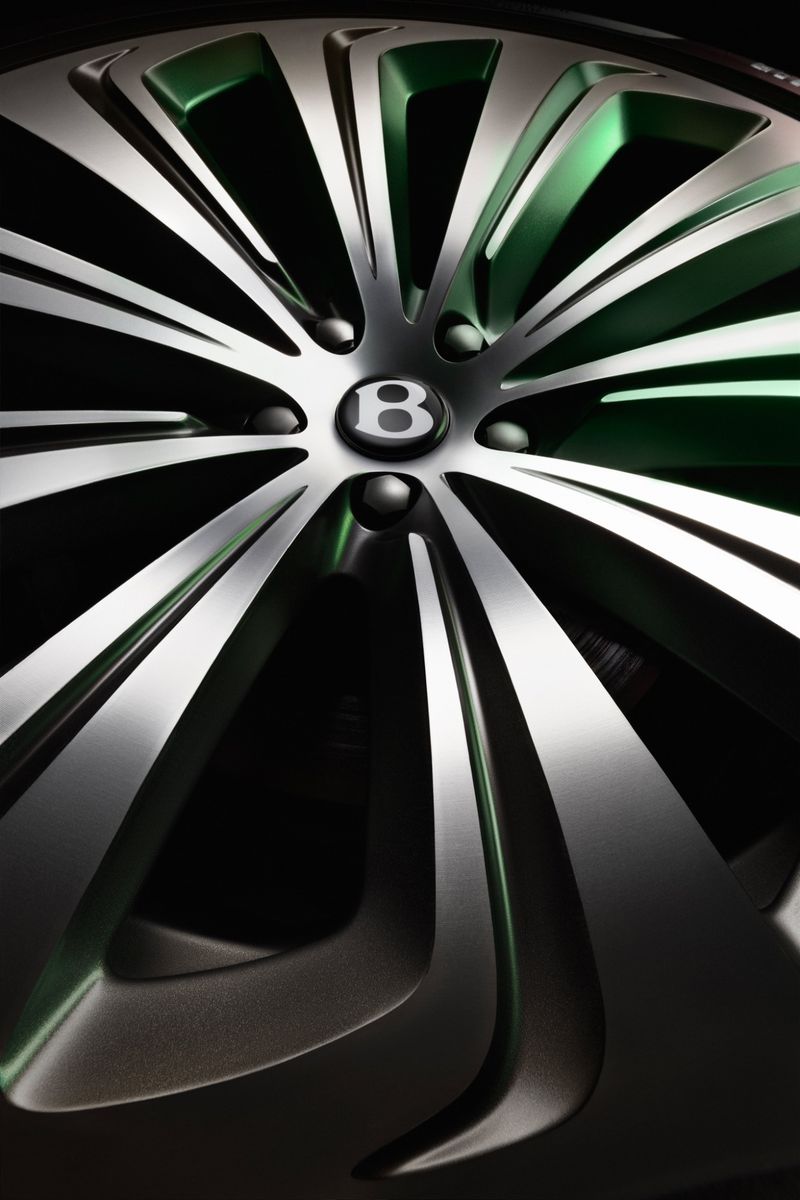 Close-up shot of a Bentley car wheel with a silver and green finish, showcasing the elegant design and iconic 'B' logo.