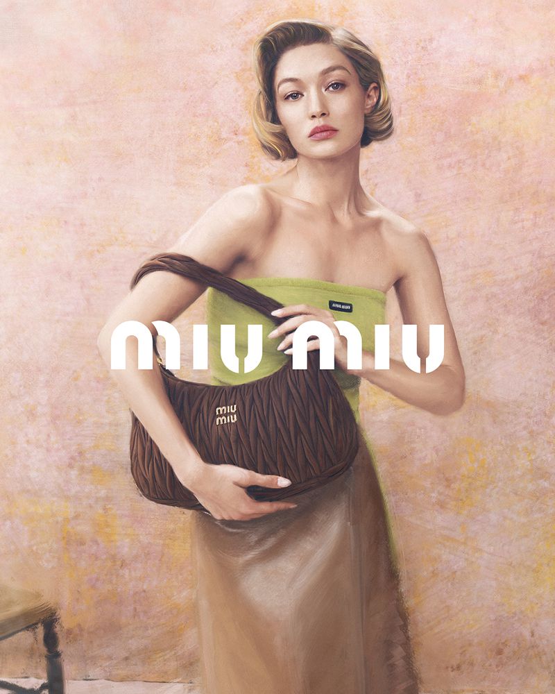 Fashion shot of a woman with a light green top and light brown skirt holding a brown purse in front of a pink and tan background.