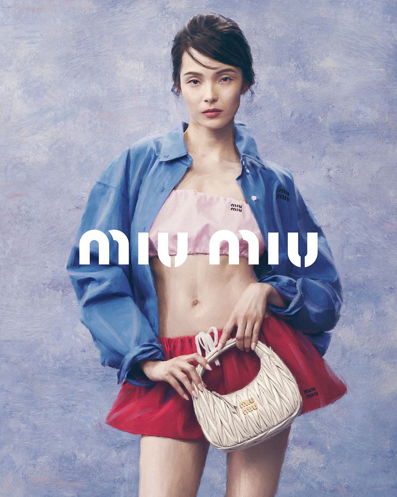 Fashion shot of a young woman wearing a pink top, red skirt, and blue jacket, holding a purse with Miu Miu logo with a soft background.