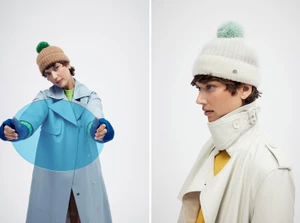 Model wearing a beanie with a fluffy pom pom and a trench coat against a white background for Helen Kaminski