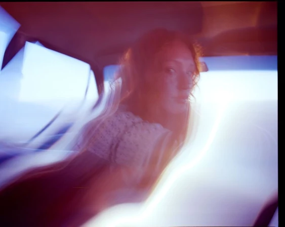 Blurred motion of a woman in a vintage car interior during the daytime, showcasing retro automotive travel and nostalgic aesthetic.