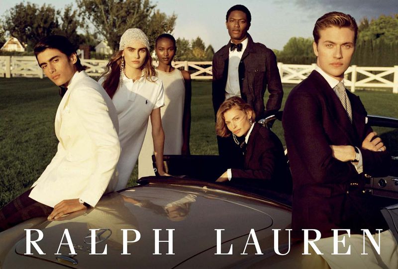 Group of fashion models posing in elegant formal wear outdoors with a vintage car, showcasing classic and sophisticated style.