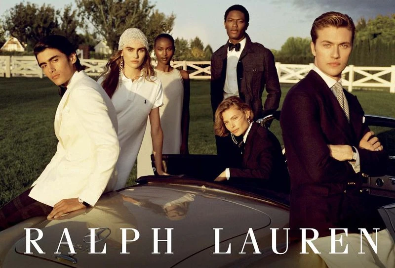 Group of fashion models posing in elegant formal wear outdoors with a vintage car, showcasing classic and sophisticated style.