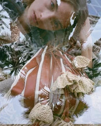 Multiple exposure fashion photograph featuring a model portrait layered over palm trees and a striped leather handbag