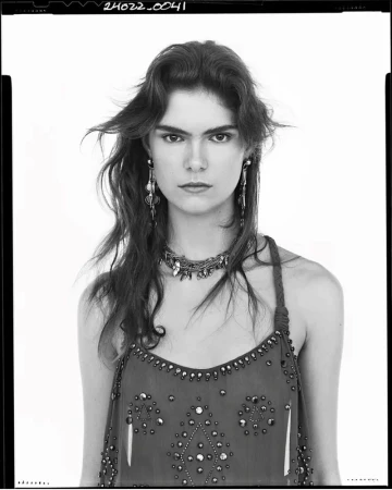 Portrait of a female model wearing embellished dress and statement jewelry against a plain background